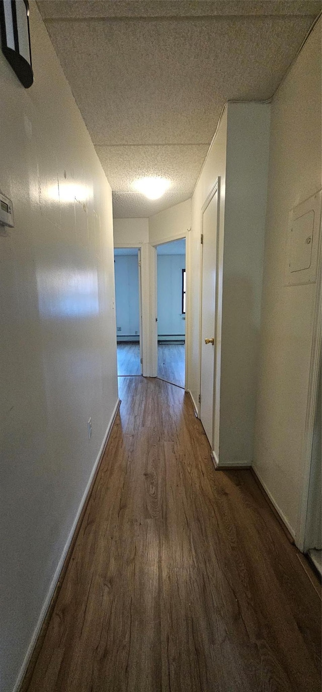 hallway with hardwood / wood-style flooring and baseboard heating