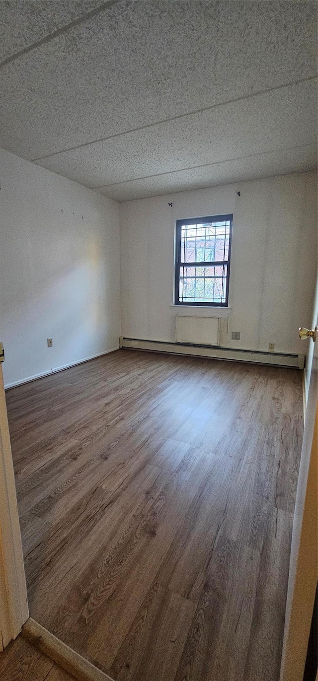 unfurnished room with hardwood / wood-style flooring and baseboard heating