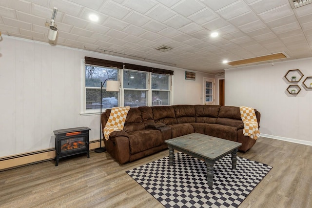 living room featuring a wood stove, light hardwood / wood-style flooring, and a baseboard heating unit