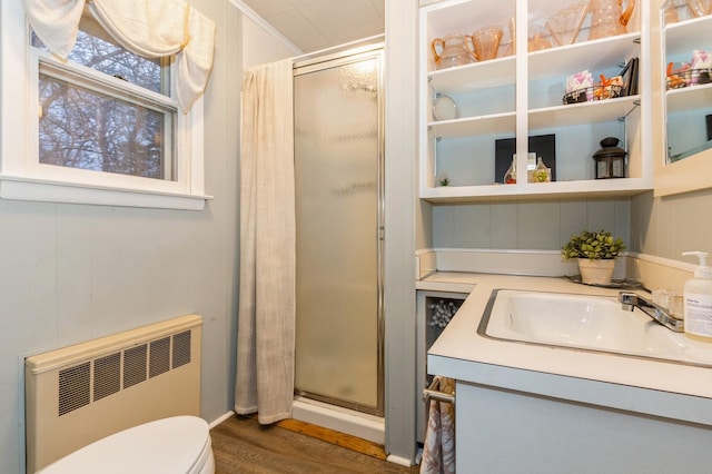 bathroom with radiator, a shower with door, wood-type flooring, and toilet