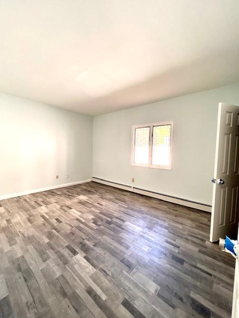 spare room with dark hardwood / wood-style floors and a baseboard radiator