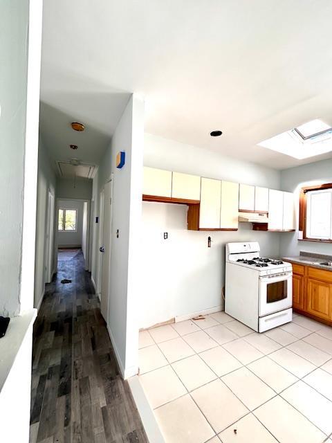 kitchen with light hardwood / wood-style floors, a skylight, and gas range gas stove