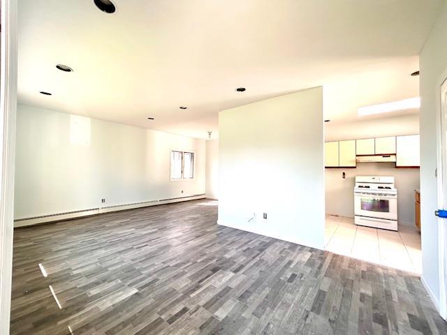 unfurnished living room with hardwood / wood-style floors and a baseboard radiator