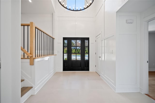 entryway featuring a notable chandelier, a towering ceiling, and light tile patterned floors