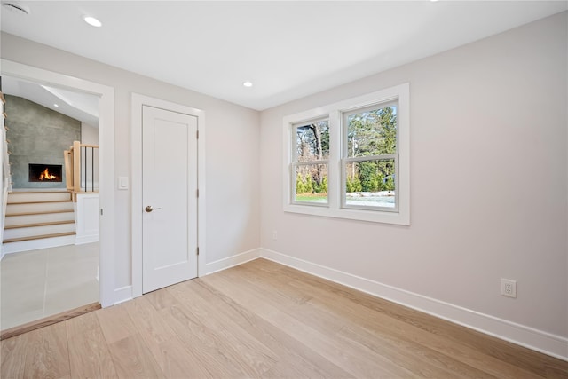 unfurnished room with a large fireplace and light wood-type flooring