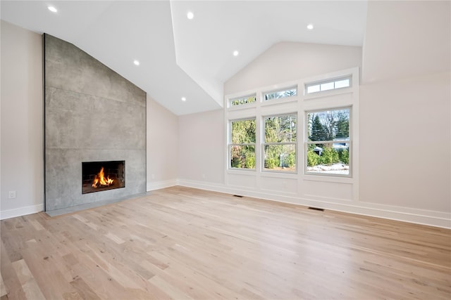 unfurnished living room with a fireplace, high vaulted ceiling, and light hardwood / wood-style floors