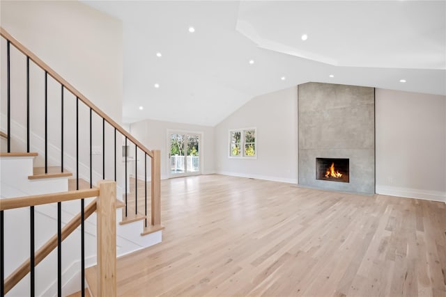 unfurnished living room with a fireplace, light hardwood / wood-style flooring, and lofted ceiling