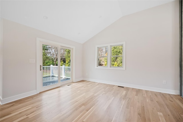 empty room with vaulted ceiling, light hardwood / wood-style flooring, and plenty of natural light