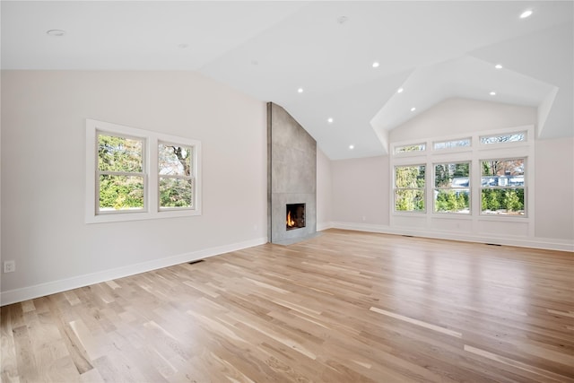 unfurnished living room featuring lofted ceiling, a fireplace, and light hardwood / wood-style flooring