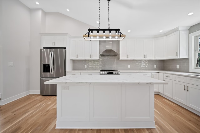 kitchen featuring a center island, wall chimney range hood, appliances with stainless steel finishes, and light hardwood / wood-style flooring