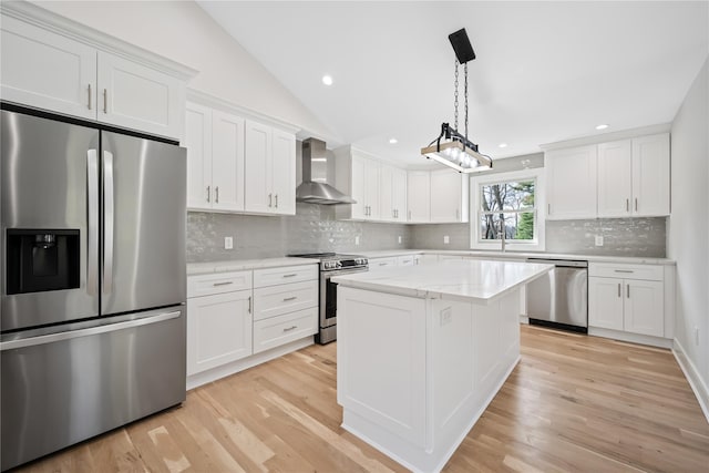 kitchen featuring wall chimney exhaust hood, decorative backsplash, light hardwood / wood-style floors, white cabinetry, and stainless steel appliances