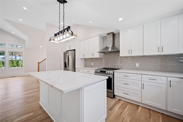 kitchen with white cabinets, appliances with stainless steel finishes, light hardwood / wood-style floors, and wall chimney range hood