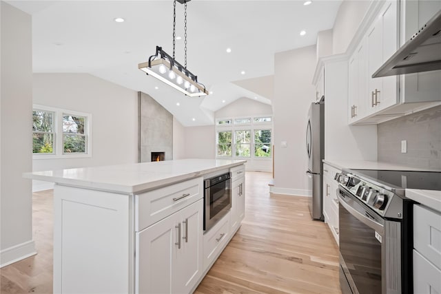 kitchen featuring white cabinets, a kitchen island, appliances with stainless steel finishes, and pendant lighting