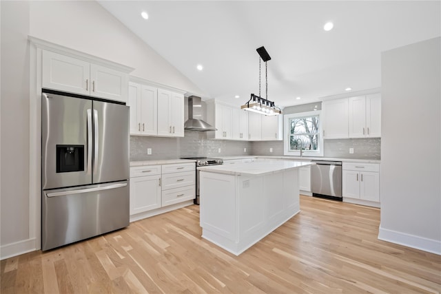 kitchen featuring wall chimney exhaust hood, light wood-type flooring, white cabinetry, and appliances with stainless steel finishes