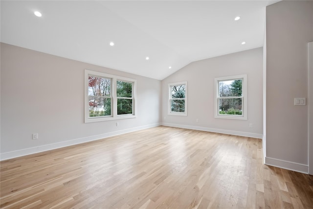 spare room with a healthy amount of sunlight, vaulted ceiling, and light wood-type flooring