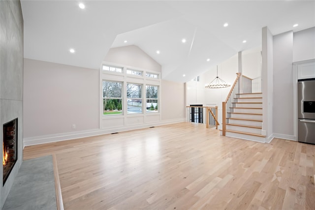 unfurnished living room with a fireplace, light hardwood / wood-style floors, and high vaulted ceiling