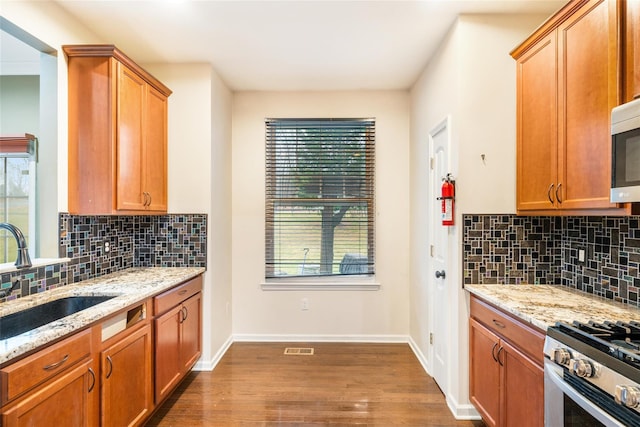 kitchen with decorative backsplash, dark hardwood / wood-style flooring, light stone countertops, and sink