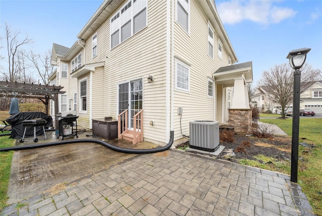 rear view of house featuring a pergola, a patio area, and central air condition unit