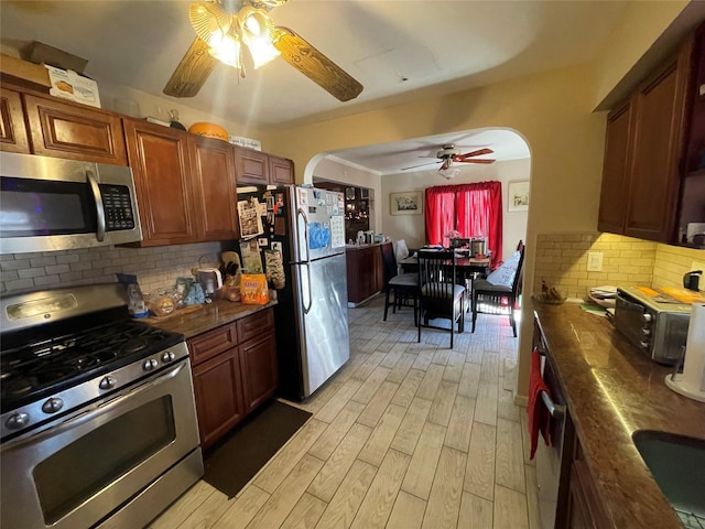 kitchen featuring decorative backsplash, appliances with stainless steel finishes, light hardwood / wood-style floors, and ceiling fan