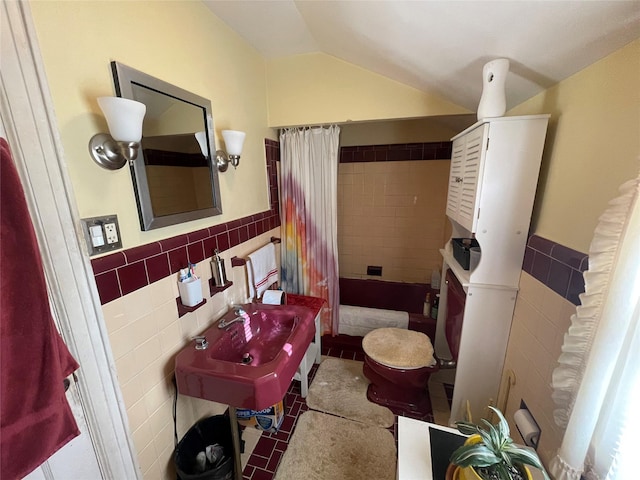 bathroom featuring lofted ceiling, sink, and tile walls