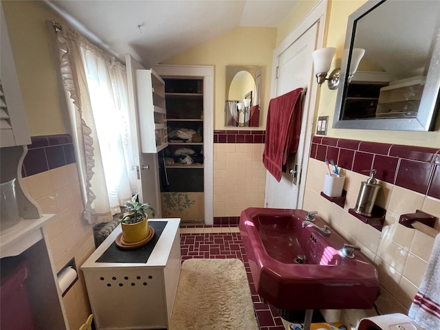 bathroom with tile walls, lofted ceiling, and sink