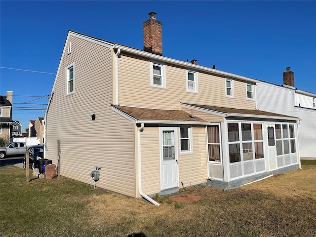 back of house with a lawn and a sunroom