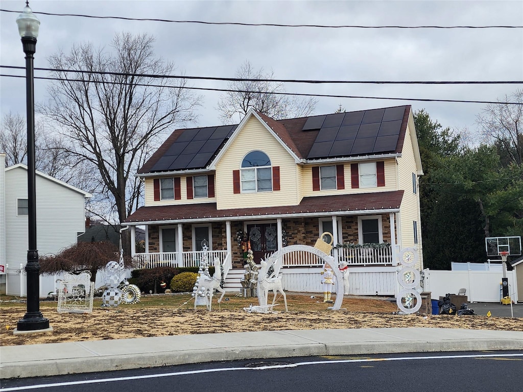 colonial-style house featuring solar panels and a porch