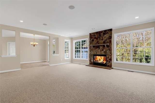 unfurnished living room featuring a chandelier, light colored carpet, a stone fireplace, and a healthy amount of sunlight