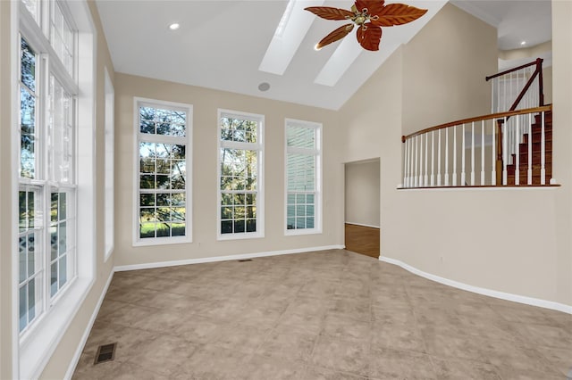 interior space with a skylight, high vaulted ceiling, and ceiling fan