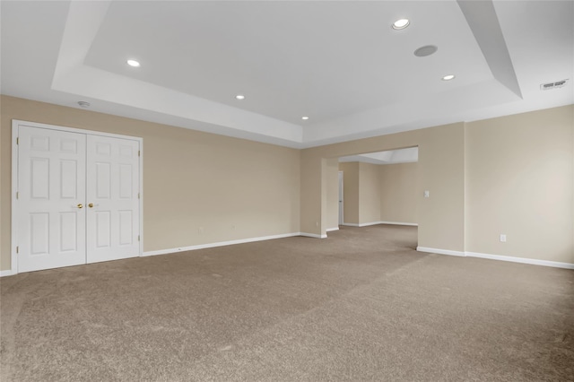 spare room with carpet flooring and a raised ceiling