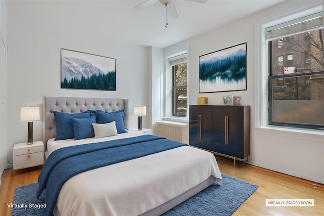 bedroom featuring ceiling fan, hardwood / wood-style floors, and radiator heating unit