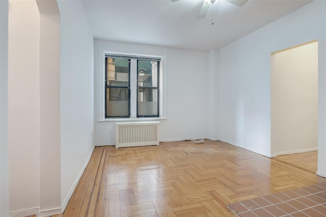 empty room featuring radiator, ceiling fan, and light parquet flooring