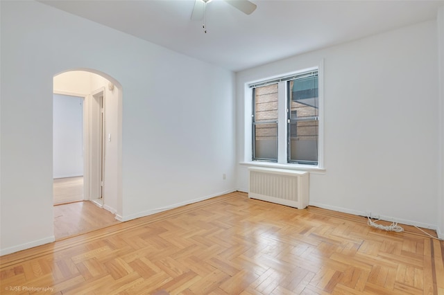 unfurnished room with ceiling fan, radiator heating unit, and light parquet floors