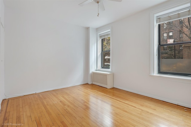 unfurnished room featuring ceiling fan, light wood-type flooring, and radiator heating unit