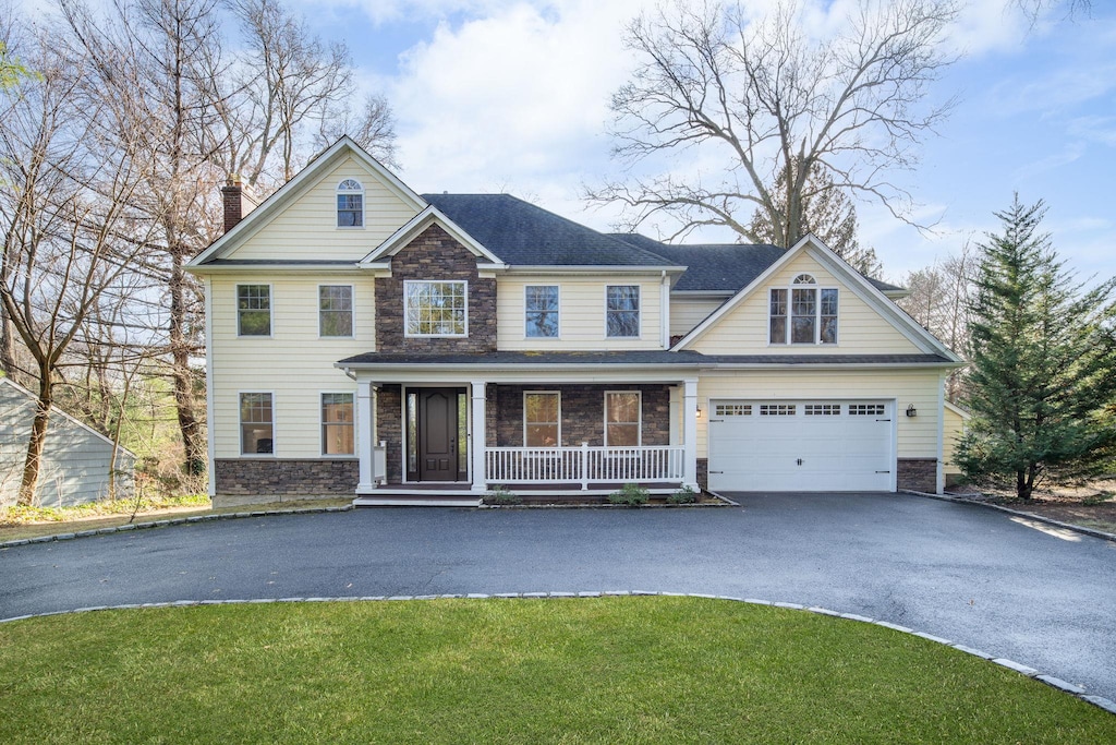 view of front of house featuring covered porch, a garage, and a front yard