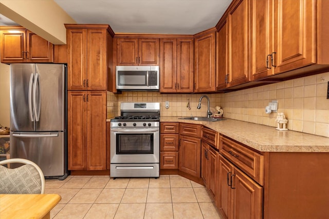 kitchen with appliances with stainless steel finishes, backsplash, light tile patterned floors, and sink