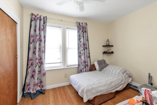 bedroom with a closet, light hardwood / wood-style flooring, multiple windows, and ceiling fan