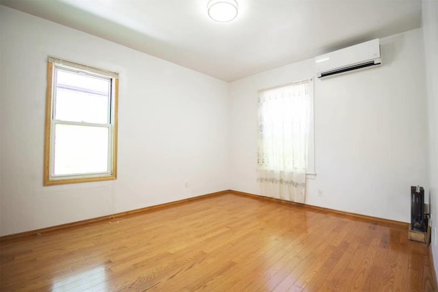 unfurnished room with light wood-type flooring and a wall unit AC