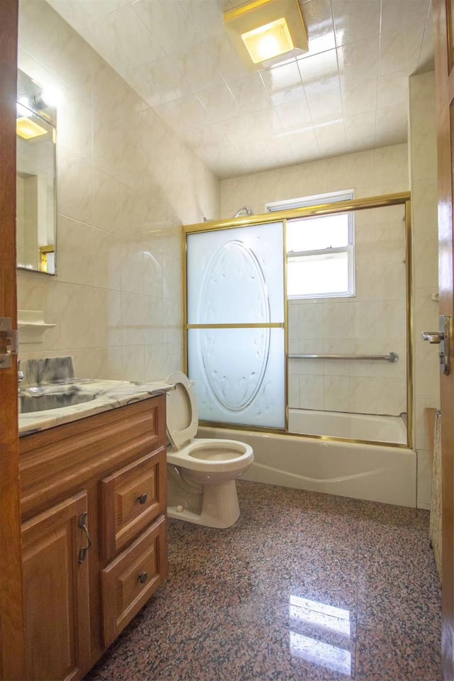 full bathroom with vanity, toilet, shower / bath combination with glass door, and tile walls