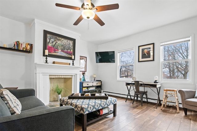 living room featuring hardwood / wood-style floors, ceiling fan, and a baseboard heating unit