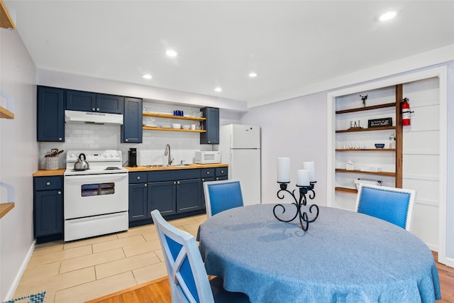 kitchen featuring white appliances, sink, decorative backsplash, light wood-type flooring, and blue cabinetry