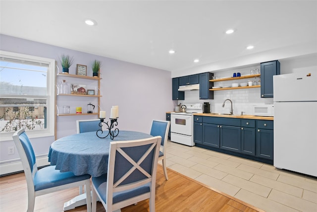 kitchen with white appliances, sink, light hardwood / wood-style flooring, blue cabinetry, and tasteful backsplash