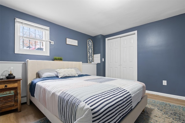 bedroom with baseboard heating, dark wood-type flooring, and a closet