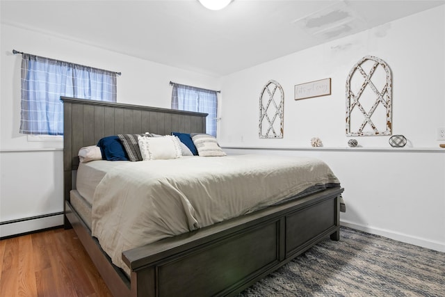 bedroom with dark hardwood / wood-style floors and a baseboard radiator