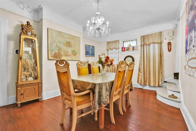 dining area with dark hardwood / wood-style flooring, ornamental molding, and an inviting chandelier