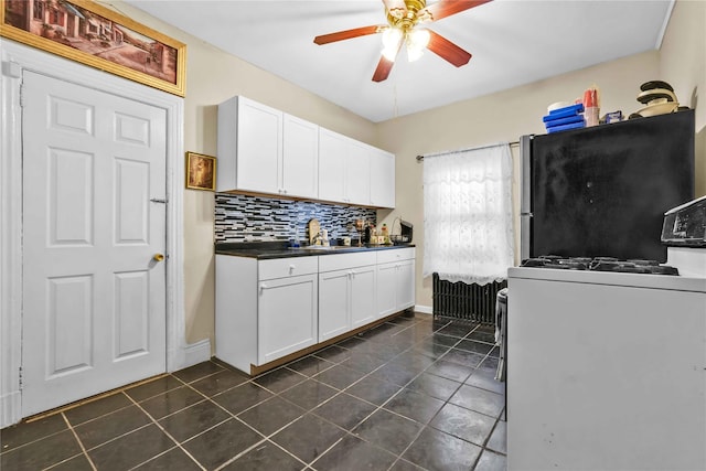 kitchen with backsplash, ceiling fan, stainless steel fridge, gas range gas stove, and white cabinetry