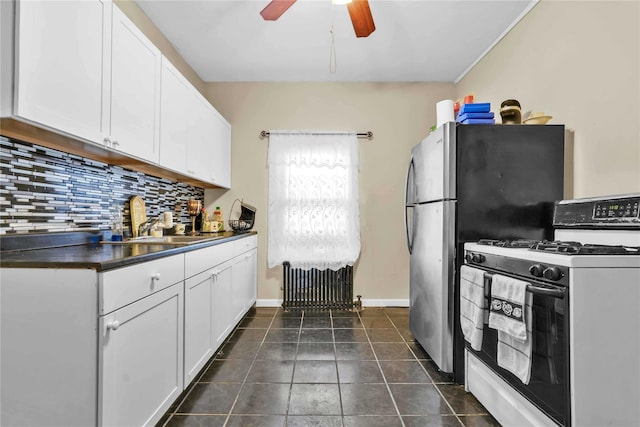 kitchen with backsplash, white gas stove, white cabinets, and sink