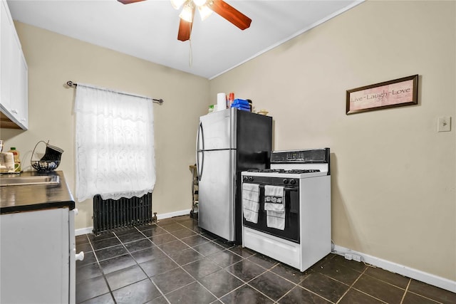 kitchen featuring radiator, stainless steel fridge, dark tile patterned floors, white cabinetry, and white range with gas cooktop