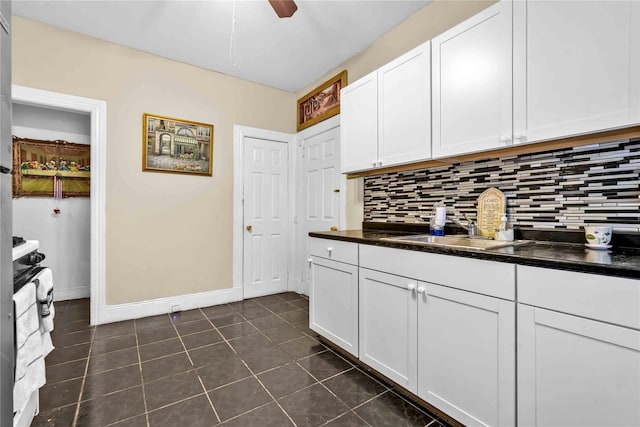 kitchen featuring white cabinets, decorative backsplash, dark tile patterned floors, and sink