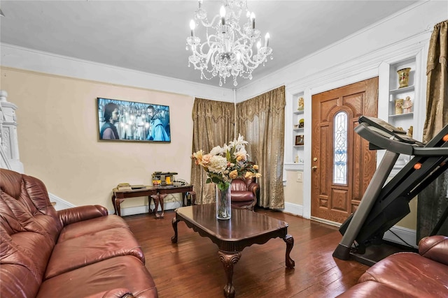 living room featuring built in shelves, dark hardwood / wood-style flooring, crown molding, and a chandelier